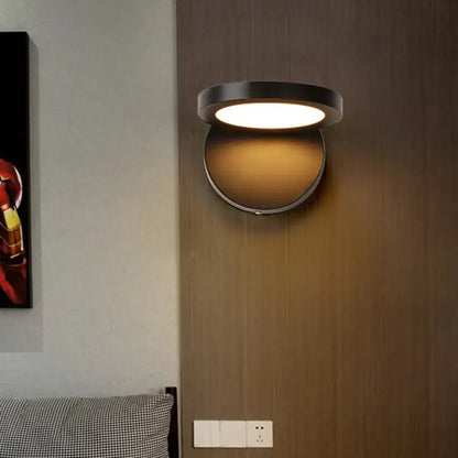 Modern black circular wall light fixture with warm diffused glow for bedroom use providing stylish lighting