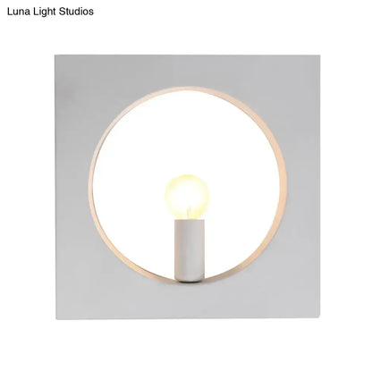 Minimalist wall lamp with circular wooden frame, white matte square backplate, and medium base candle bulb fixture