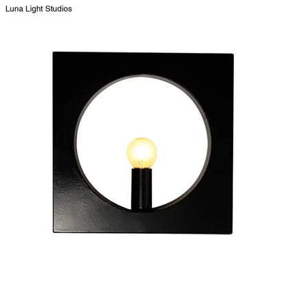 Modern black wall lamp with square glass fixture and circular cutout framing illuminated medium base bulb
