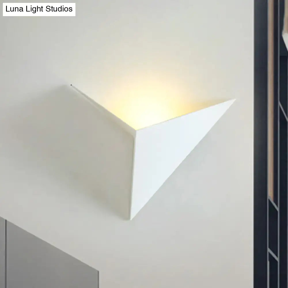 Modern black and white triangle sheet wall lamp with smooth minimalist design emitting warm light for bedroom use