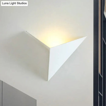 Modern black and white triangle sheet wall lamp with smooth minimalist design emitting warm light for bedroom use