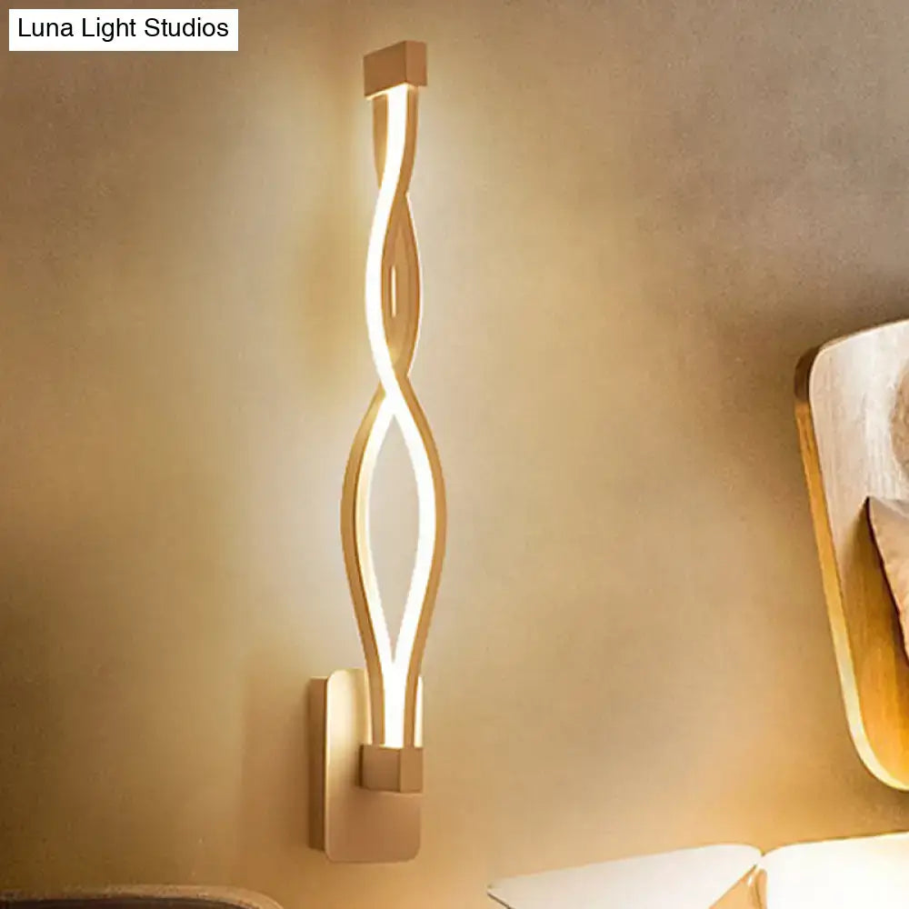 Modern gold-toned wall light sconce with a sleek twisted design providing warm ambient lighting for living rooms 110v-120v
