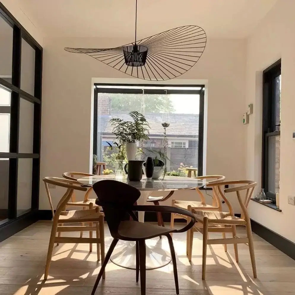Modern black metal fan-shaped decorbites designer pendant with woven wire design hanging above dining table