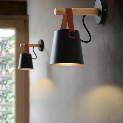 Modern black wooden wall light with a matte black conical lampshade suspended by red leather strap decorbites black wooden wall