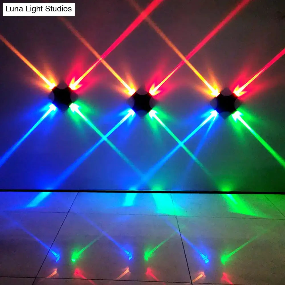 Modern black x shaped wall mount lamp with rgb color led projecting vibrant red green and blue beams on ceiling