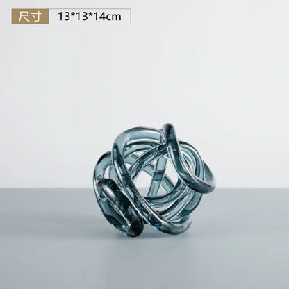 A translucent blue glass coil ball decorative figurine with intertwined smooth loops for living room decor