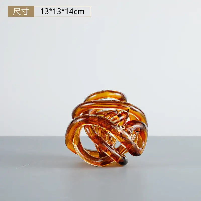 A translucent amber glass hair claw with a twisted design next to a modern blue amber and gray glass coil ball decorative figurine
