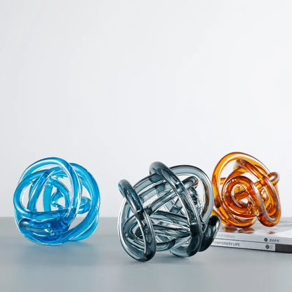 Three translucent glass coil ball decorative figurines in blue, amber, and smoky gray for modern living room decor