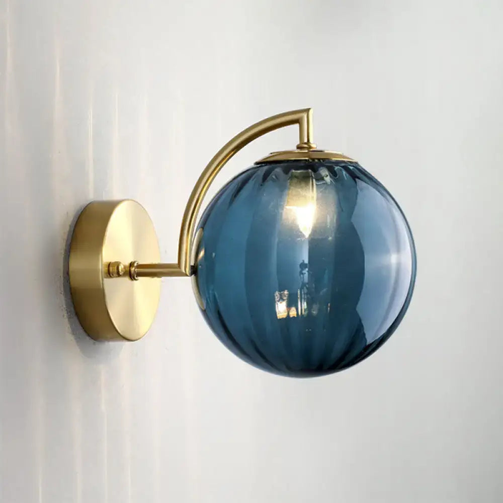 Modern blue and gold finish ribbed glass wall sconce with polished brass mounting plate and curved arm for bedroom light