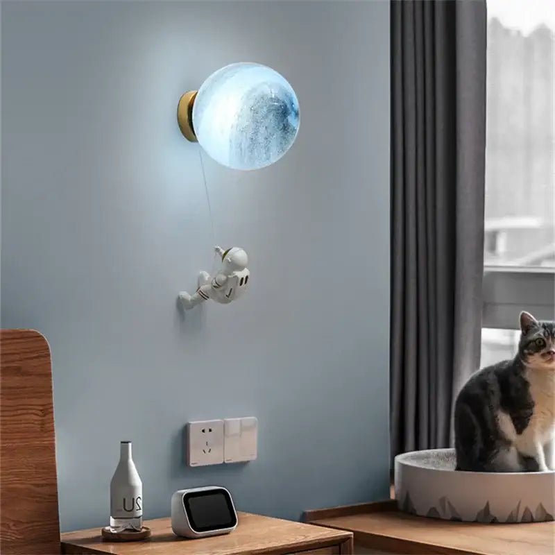 Modern blue astronaut moon wall lamp with a translucent globe and gold base featuring decorbites astronaut moon design
