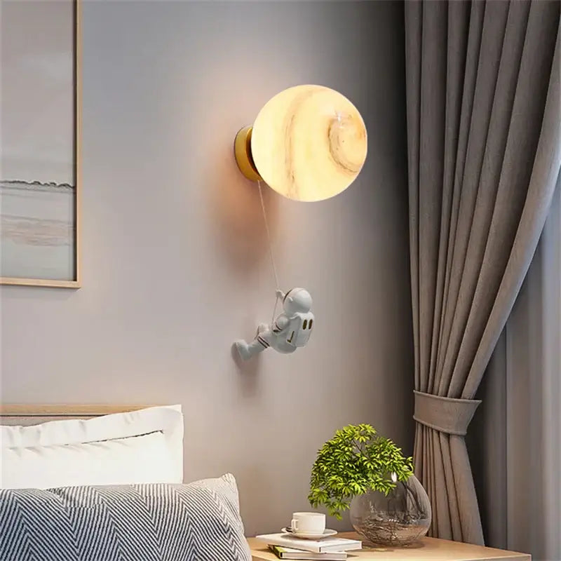 Modern blue astronaut moon wall lamp features a whimsical white astronaut figurine on a warm amber globe decorbites astronaut moon