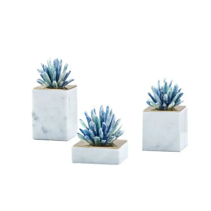 Set of three white marble base square planters with gold trim holding blue and green decorbites crystal flower succulents