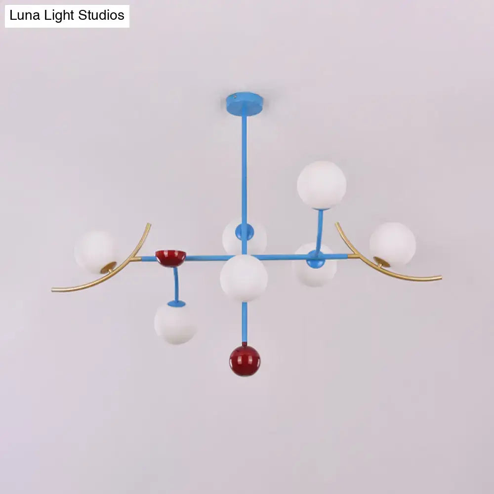 Modern blue and gold metal lamp fixture with white opal glass ball shades and red accent spheres for dining room island