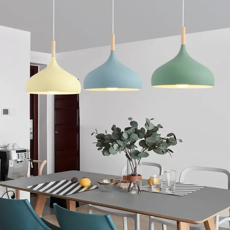 Modern pendant lights with matte pastel shades in blue, pink, and green with wood accent help create a stylish kitchen