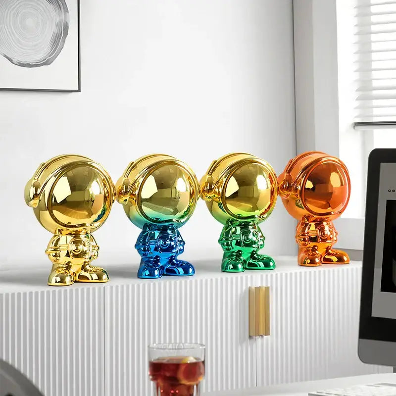 Four glossy metallic astronaut statues in gold blue green and orange for modern living room decor by decorbites astronaut statue
