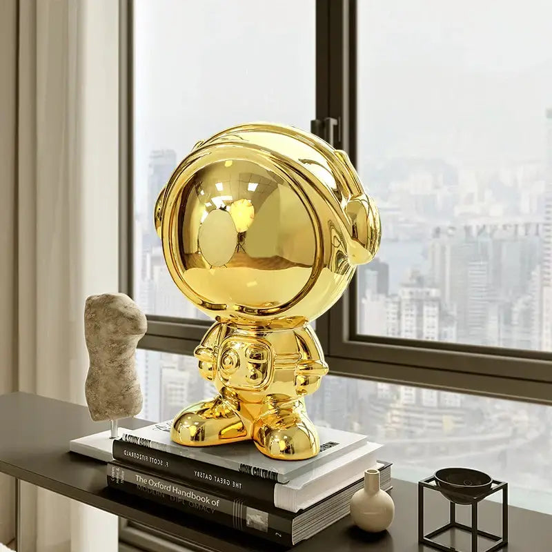 Shiny gold decorbites astronaut statue with reflective surface and rounded cartoonish design for living room decor