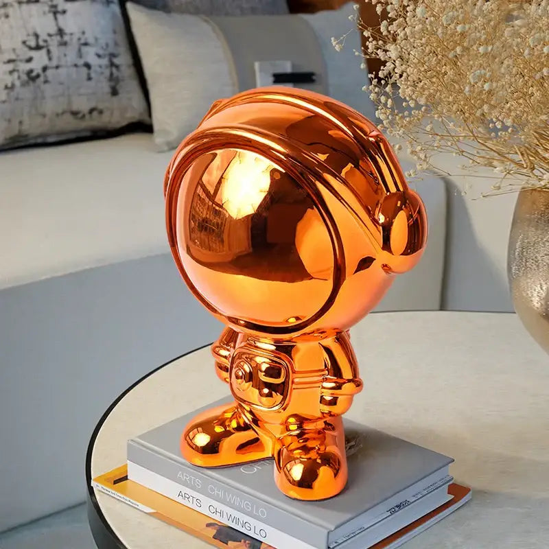 Shiny orange decorbites astronaut statue with metallic finish for modern blue and red gradient living room decor