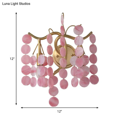 A delicate pink branch design wall lamp with a gold frame and oval rose quartz slices for bedroom sconce use