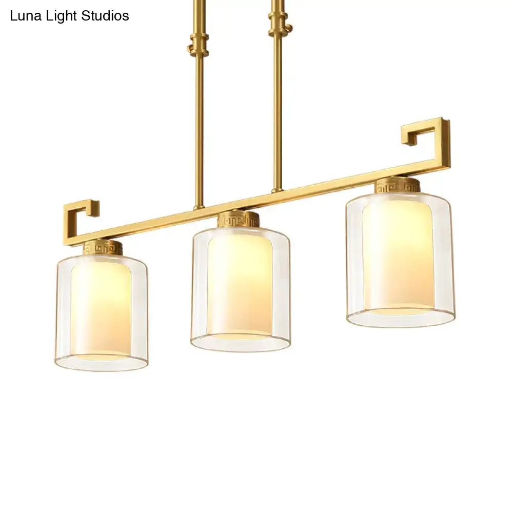 Gold-finished decorbites™ classic cylinder island lighting with three opal glass pendulum shades emitting warm glow
