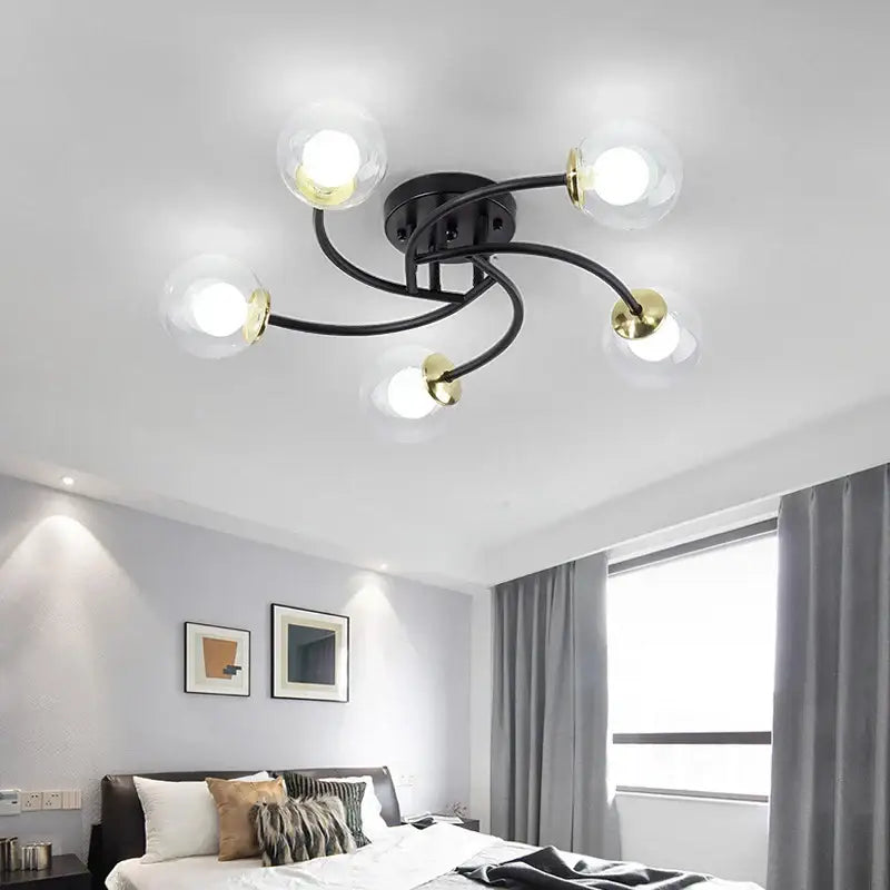 Modern brass ceiling light fixture with black and gold finish and five clear glass bulb globes for kitchen lighting