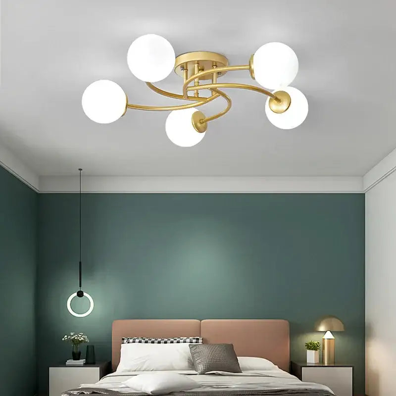Modern brass ceiling light fixture with five frosted glass bulb shades in a curved design for kitchen lighting