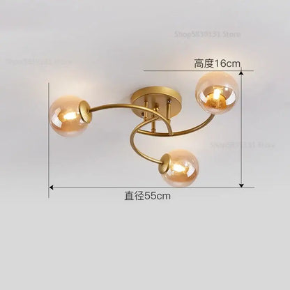 Modern brass ceiling light fixture with three gold-toned arms and amber glass bulb globes for kitchen use