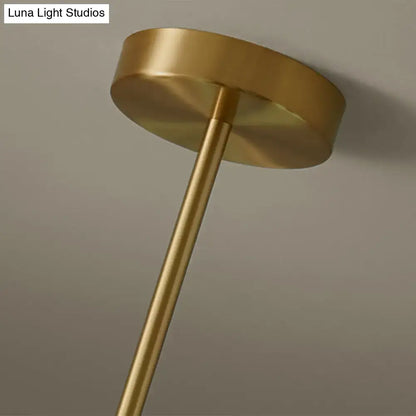 Modern brass pendant light with a brass-finished cylindrical stem and circular mounting plate featuring spherical glass shade