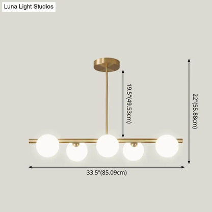 Modern brass 5-light pendant light with spherical glass shade featuring four frosted glass globes in a linear design