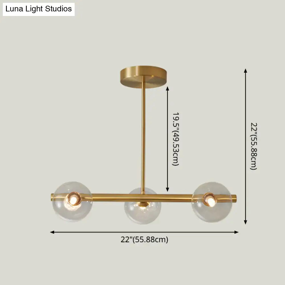 Modern brass pendant light with five spherical glass shades in a brass finish for dining room use
