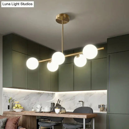 Modern brass 5-light pendant light with spherical glass shade featuring five spherical glass globes for dining room use