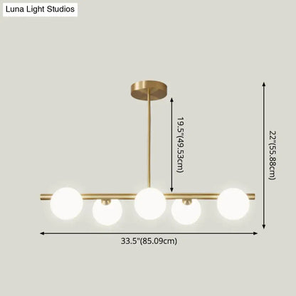 Modern brass 5-light pendant light with spherical glass shade and frosted bulbs for dining room lighting