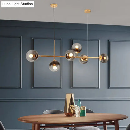 Modern brass 6 light dining room chandelier with gold-toned frame and smoke gray glass shades in spherical globes