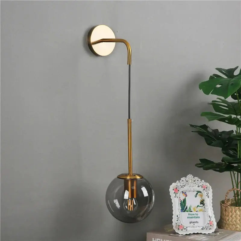 Modern brass amber glass ball wall lamp with gold-toned curved arm and smoked glass shade for bedroom decorbites glass ball
