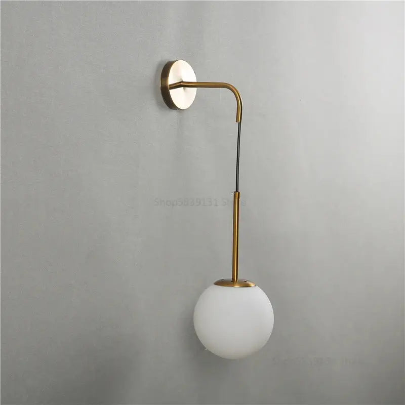 A sleek brass wall sconce with a curved arm and frosted white glass ball for modern wall lamps decorbites glass ball
