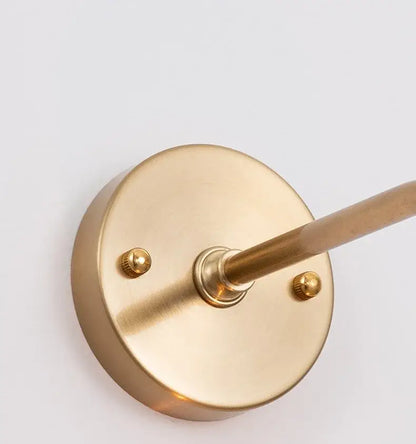 Modern brass wall lamp with decorbites amber glass featuring a sleek circular base and slender rod for living room decor