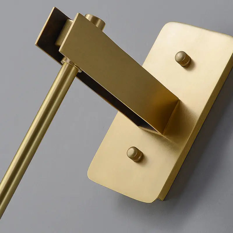 Brass-finished wall-mounted toilet paper holder with rectangular plate complements modern wall light and wall sconce designs
