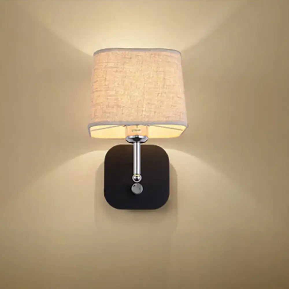 Modern wall sconce lighting with a square black base, chrome stem, spherical accent, and beige linen fabric shade