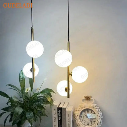 Modern brass and black glass ball pendant light with three glowing white spherical globes for dining room decorbites