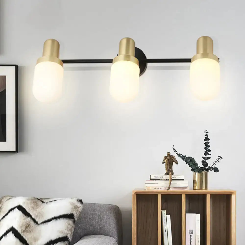 Modern brass and black glass sconce light with three frosted glass shades for bedroom wall lighting