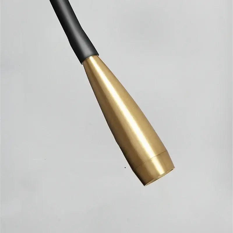 Gold-colored brass nozzle with black rubber grip on a decorbites adjustable arm copper wall lamp for bedroom reading