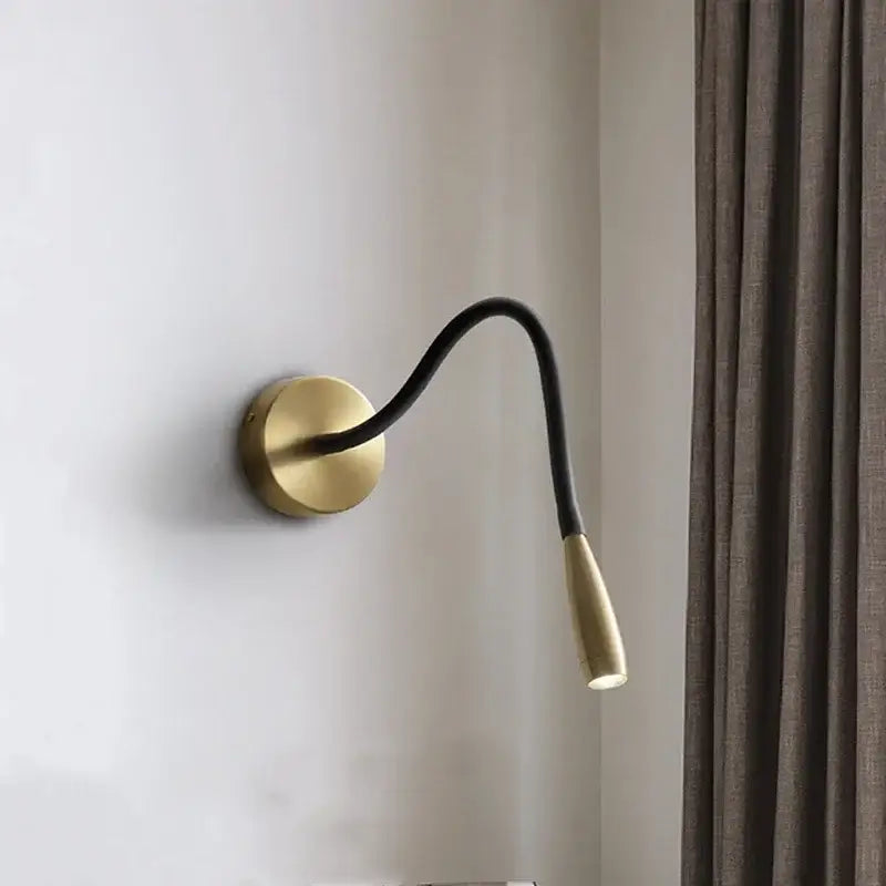 A modern brass and black wall lamp with decorbites adjustable arm copper and a light-colored ceramic head for reading