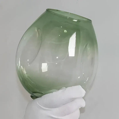 A translucent green glass bowl with embossed patterns complements modern brass and blue glass iron ball chandeliers