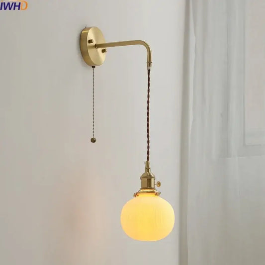 Modern brass and ceramic copper led wall lamp featuring a brass finish, twisted brown cord, and frosted glass globe bulb