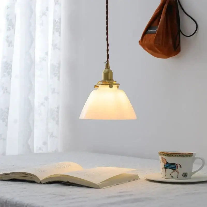 Modern brass and clear glass chandelier pendant light with off-white shade and twisted brown cord for dining room lighting