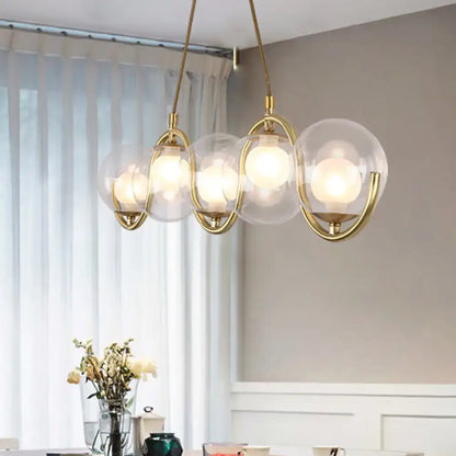 Modern brass and clear glass globe pendant light with five shades featuring adjustable chain cord length and fixture width