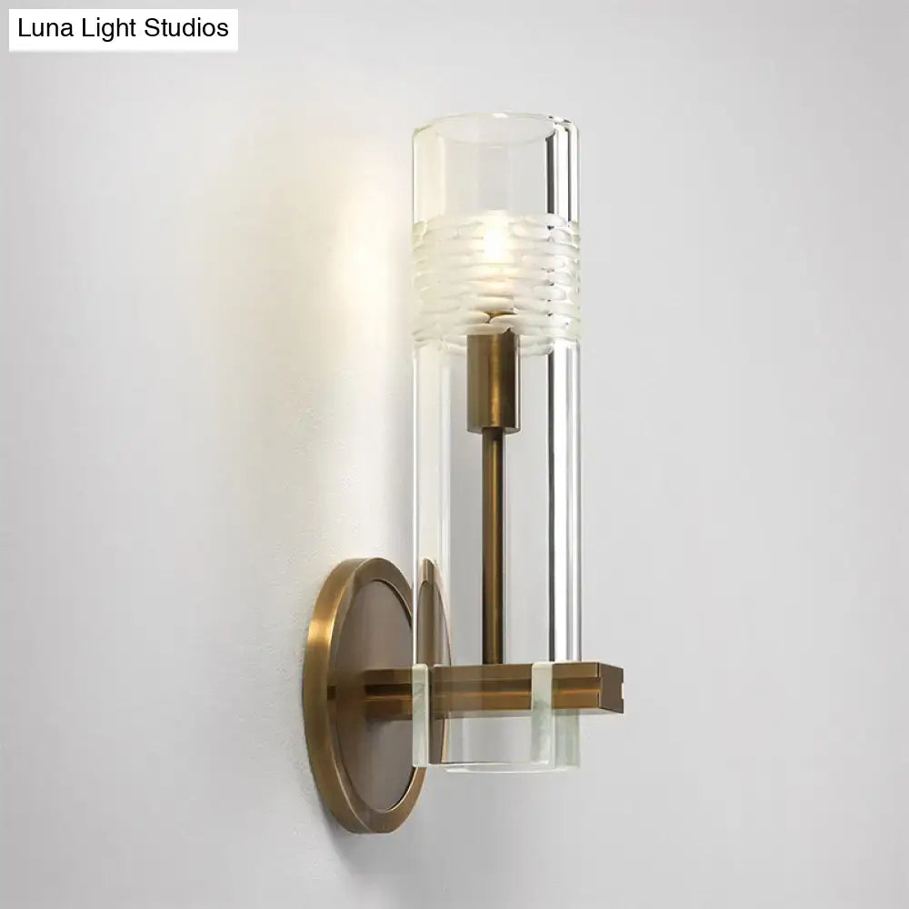 Modern brass and clear glass metal arm sconce with clear glass cylinder and brass-finished bulb wall light base
