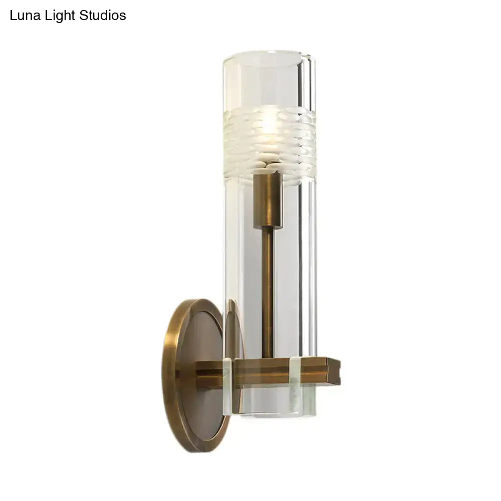 Modern brass and clear glass metal arm bulb wall sconce with a textured band for bedroom wall lighting