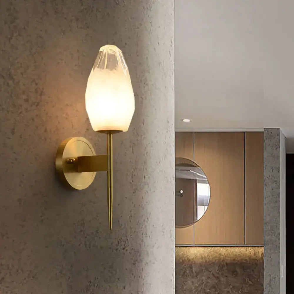 Modern brass wall lamp featuring a gold-toned sconce and clear glass frosted teardrop shade for bedroom lighting