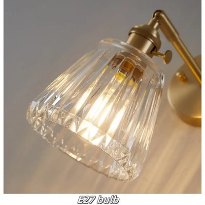 Modern brass and clear glass wall lights featuring a faceted clear glass lampshade with brass-finished arm and base decorbites clear glass