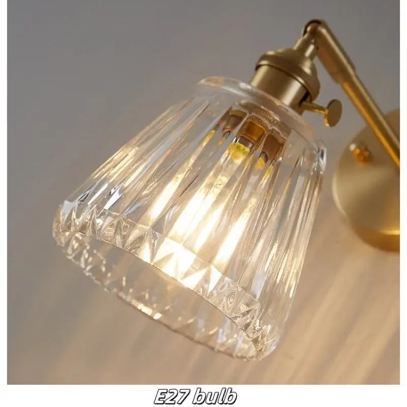 Modern brass and clear glass wall lights featuring a faceted clear glass lampshade with brass-finished arm and base decorbites clear glass